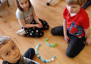 Dzieci układaja z nakrętek kształty liter.